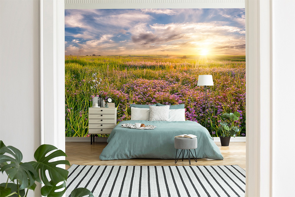 Fototapete - Schlafzimmer mit Bett und Floorteppich, dekoriert mit einer Tapete mit einem Blumenfeld bei Sonnenuntergang