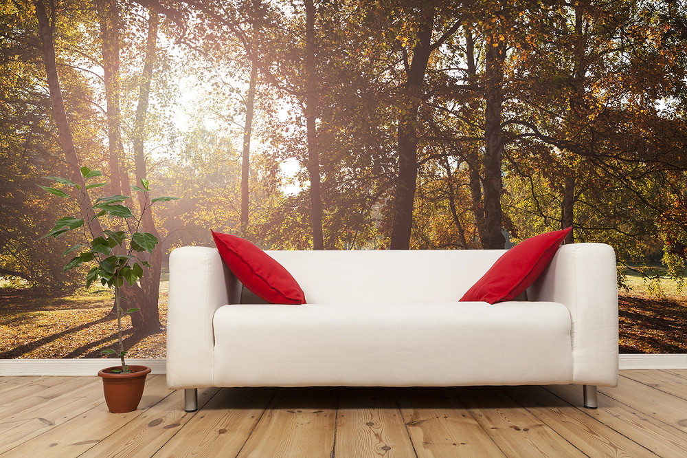 Fototapete - Helles Wohnzimmer mit weißem Sofa und roten Kissen vor einer wandfüllenden Waldlandschaft