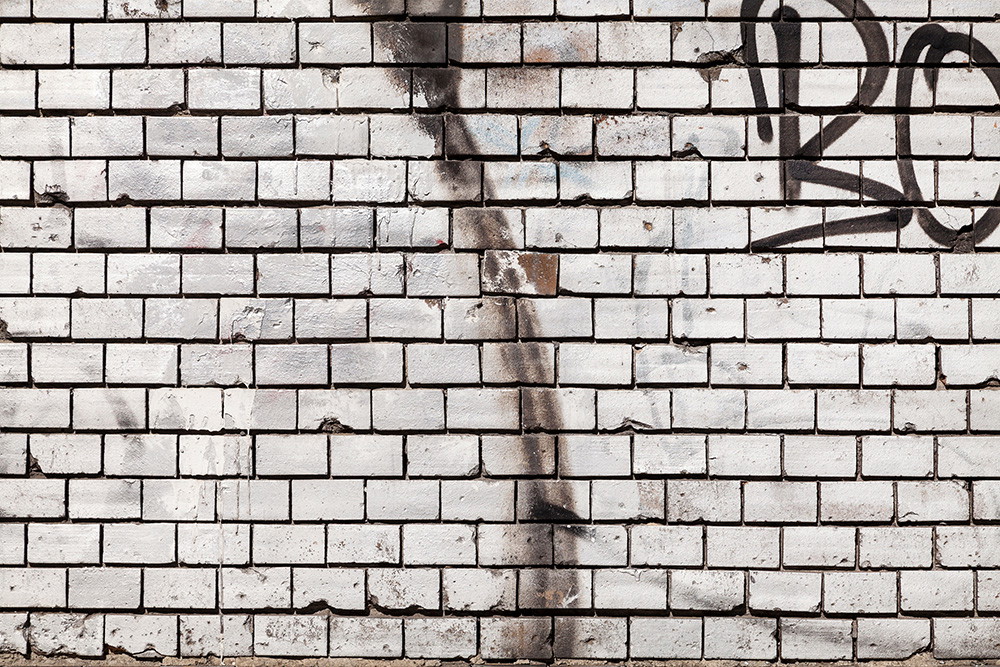 Wall mural - A white brick wall with graffiti lettering and slight signs of weathering