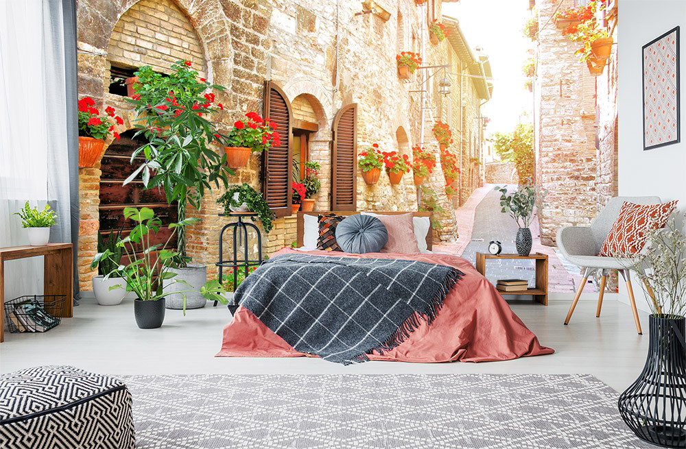 Fotomurale - Camera da letto con un Fotomurale di un pittoresco vicolo della città vecchia, decorato con fiori rossi e pareti di mattoni storici