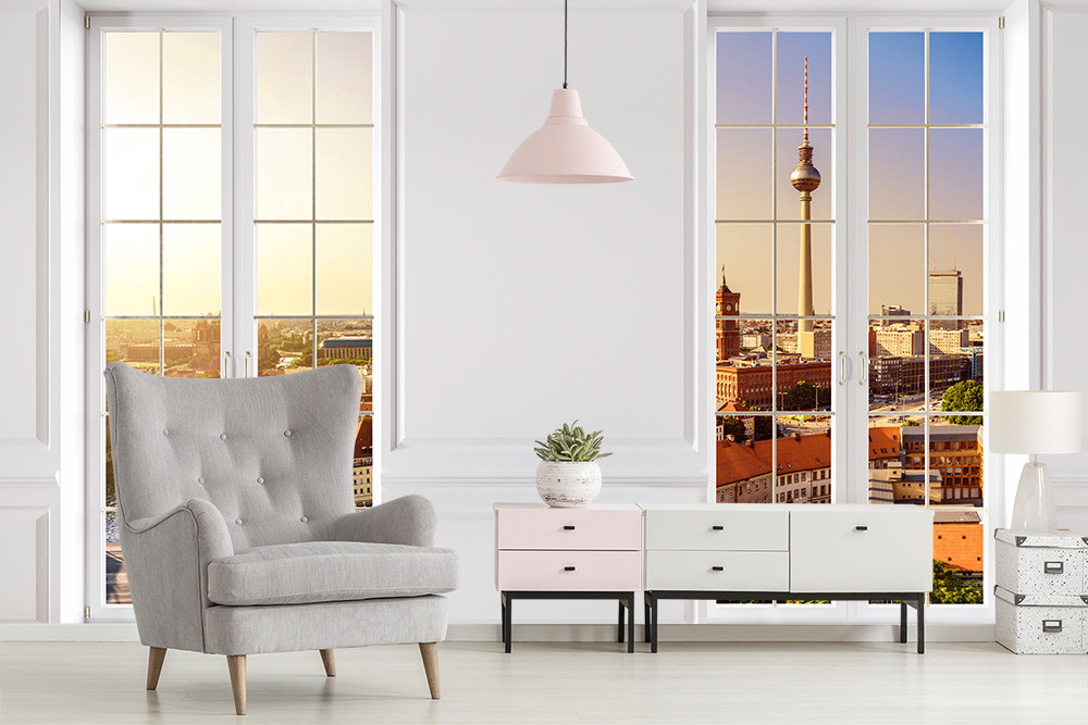 Wall mural - Living room with grey armchair, chest of drawers and view of Berlin TV tower through large window