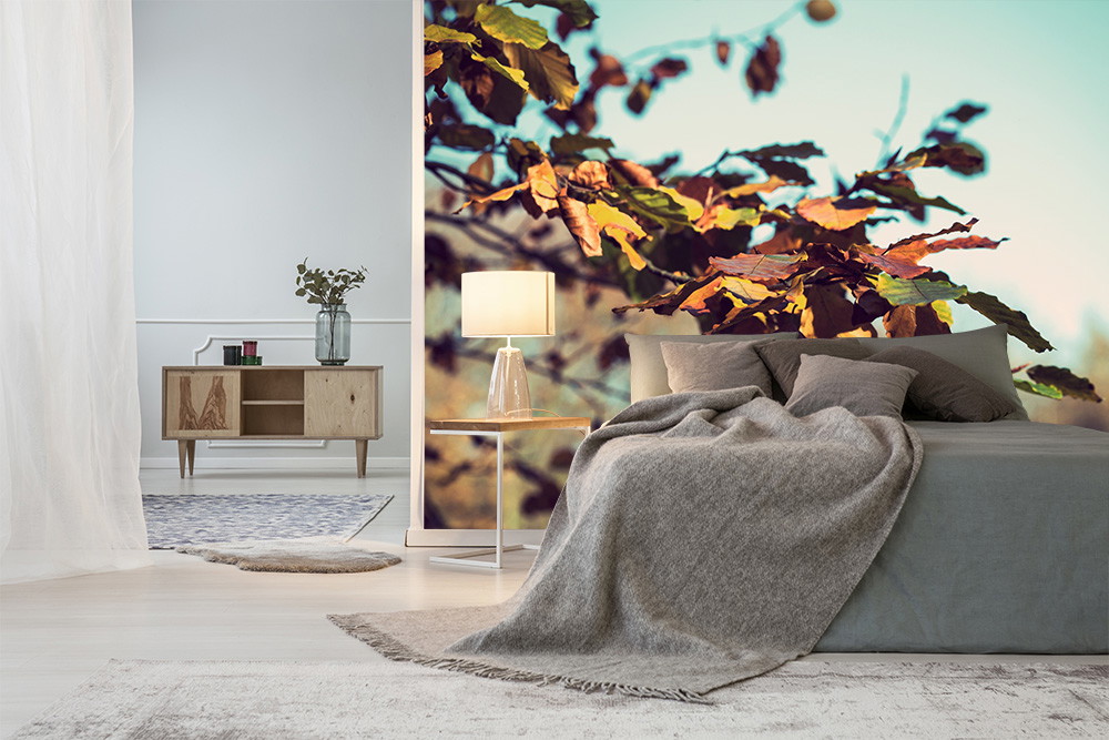 Fototapete - Schlafzimmer mit herbstlicher Fototapete, grauem Bett, und Lampe auf einem Tisch