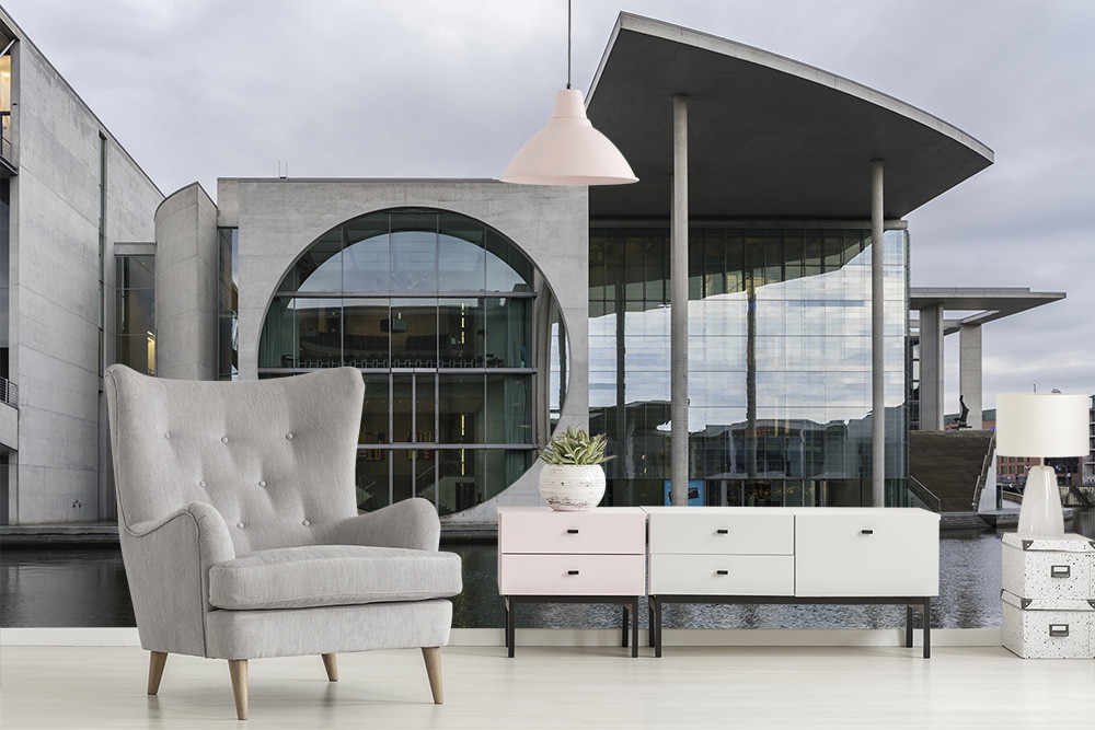 Muurschildering - Grijze fauteuil en stijlvolle ladekast voor moderne glazen architectuur