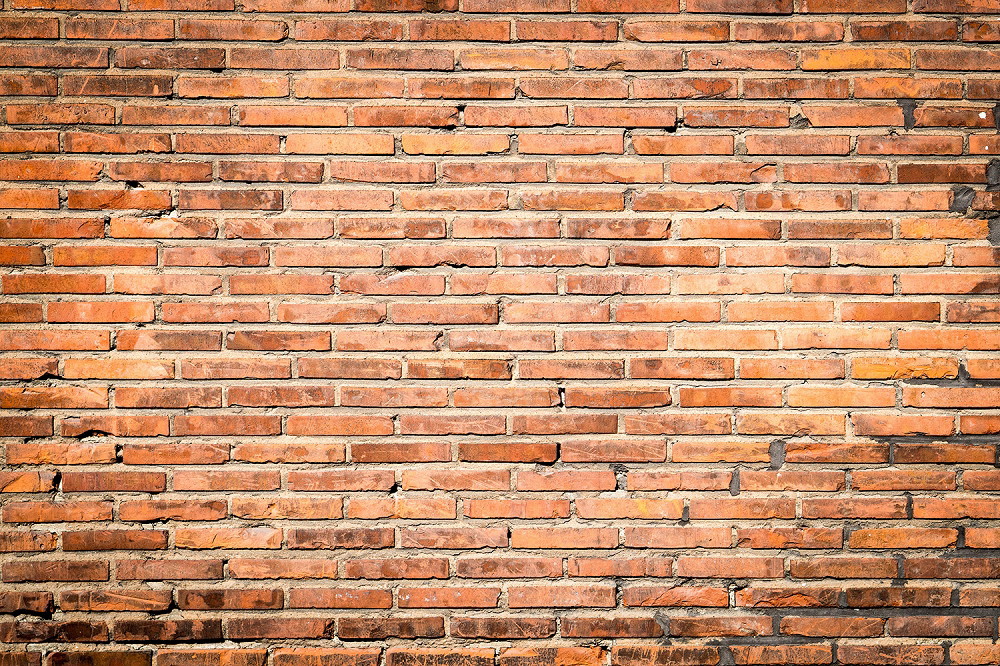 Wall mural - Close-up of a rustic brick wall with worn charm