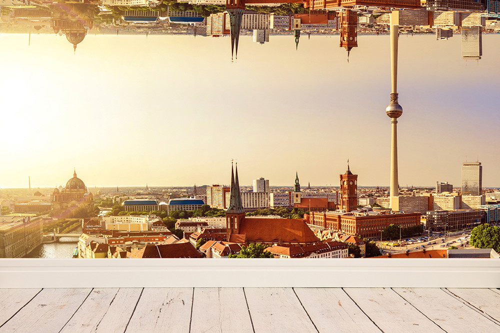 Fototapete - Panorama von Berlin mit Fernsehturm und historischen Gebäuden, im warmen Sonnenlicht gespiegelt über einem Holzboden