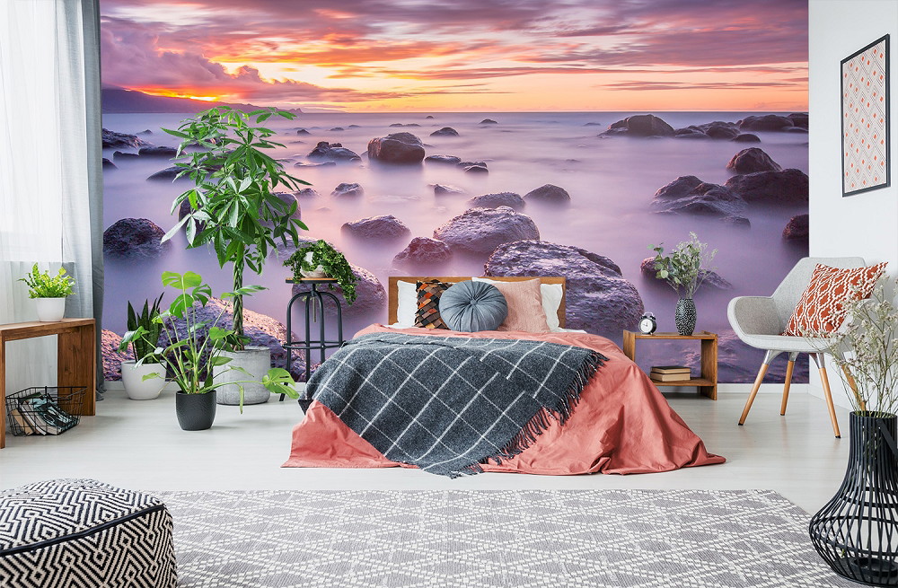 Fototapete - Schlafzimmer mit Tapete eines Sonnenuntergangs am Meer, umgeben von Pflanzen und moderner Einrichtung