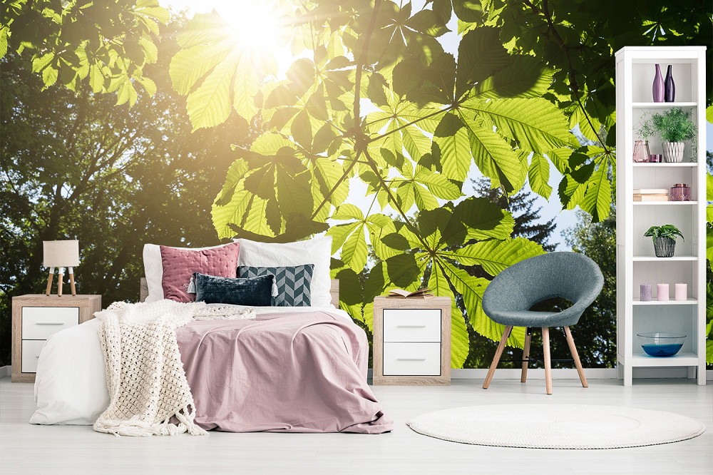 Fototapete - Helles Schlafzimmer mit Bett, modernem Sessel und Tapete mit großem Blättermotiv