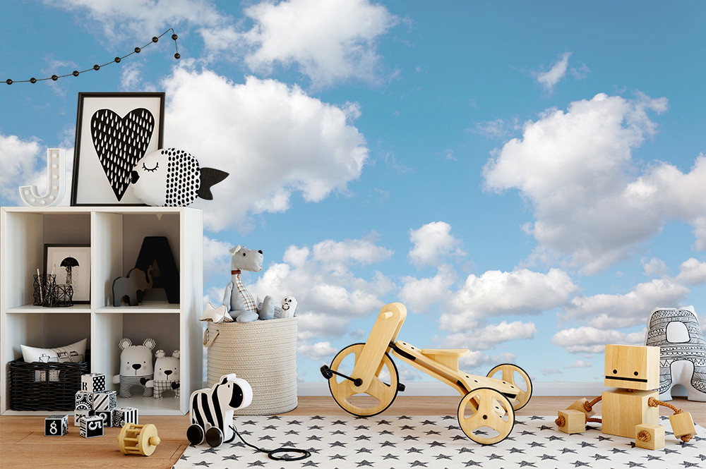 Papier peint photo - Une chambre d'enfant avec un ciel nuageux en toile de fond, des jouets et des décorations.