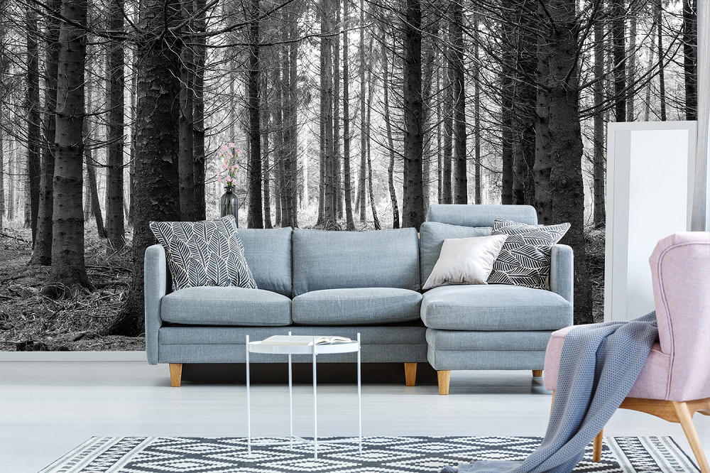 Fototapete - Helles Wohnzimmer mit grauem Sofa, davor ein Tisch und Waldmotiv an der Wand