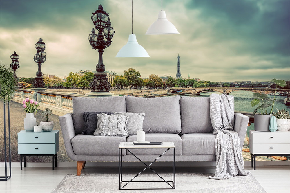 Fotomurale - Soggiorno accogliente con divano grigio e un Fotomurale che mostra un ponte di Parigi con la Torre Eiffel sullo sfondo