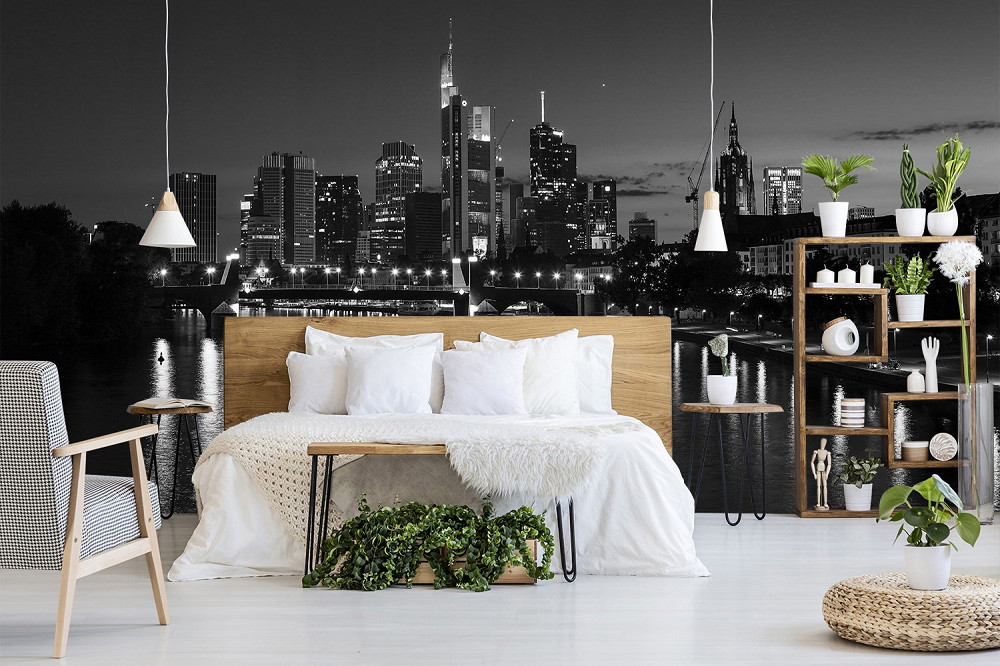 Muurschildering - Moderne slaapkamer met zwart-wit behang van de skyline van Frankfurt bij nacht op de achtergrond, ingericht met stijlvolle meubels en planten