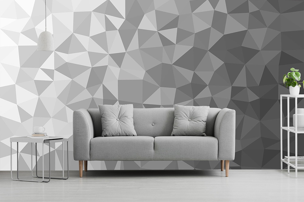 Fototapete - Wohnzimmer mit grauem Sofa vor einer grauen geometrischen Tapetenwand