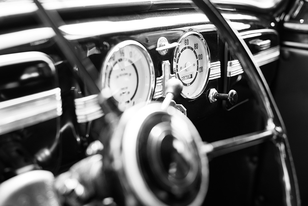 Fototapete - Detailansicht eines Oldtimer-Cockpits mit Tachometer und Lenkrad in Schwarz-Weiß