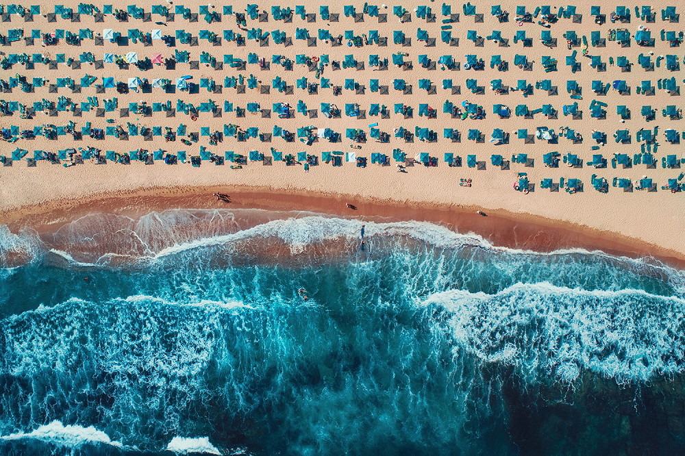 Fototapeta ścienna - Widok z lotu ptaka na plażę z parasolami i falami na brzegu