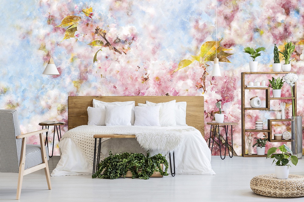 Fotomurale - Camera da letto elegante con un Fotomurale colorato, floreale e pastello, un letto a doghe di legno, cuscini bianchi, piante e mobili moderni.