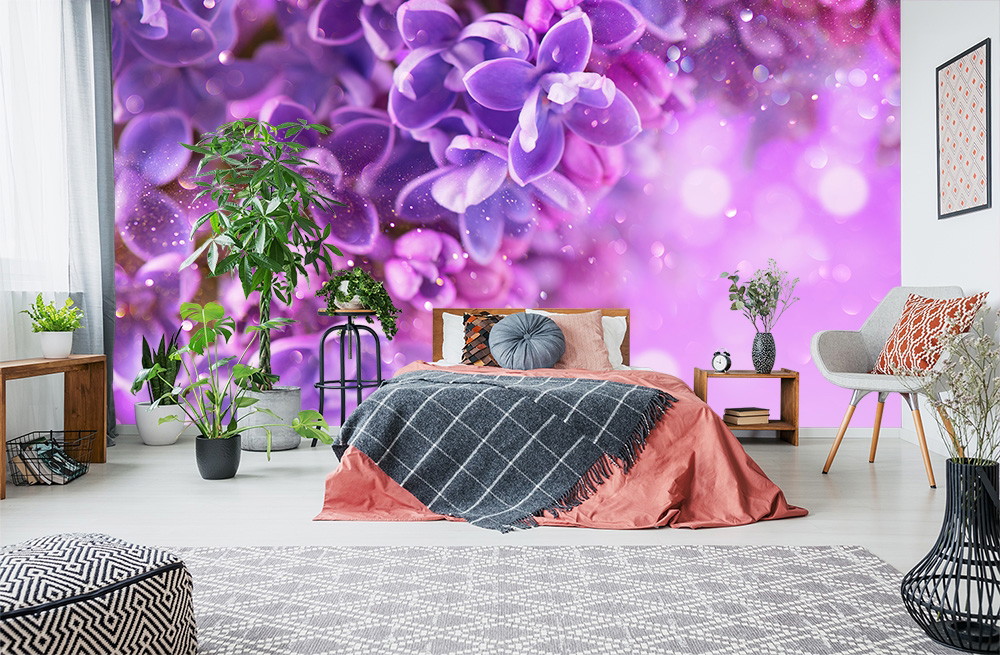 Fototapete - Schlafzimmer mit lila Blumentapete, grauem Bettüberwurf und Pflanzen für ein modernes Ambiente