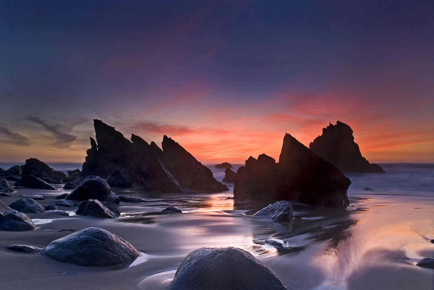 Fototapete - Felsen am Strand bei Sonnenuntergang, Himmel in orange und lila Tönen