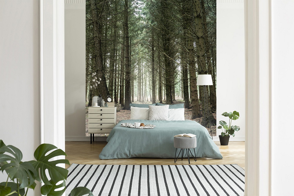 Fototapete - Stilvolles Schlafzimmer mit Waldmotiv als Fototapete hinter dem Bett, moderne Einrichtung mit Pflanzen und hellem Teppich