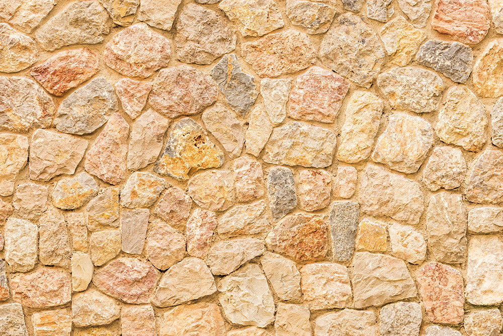 Wall mural - Detailed view of a natural stone wall in various shades of beige and pink