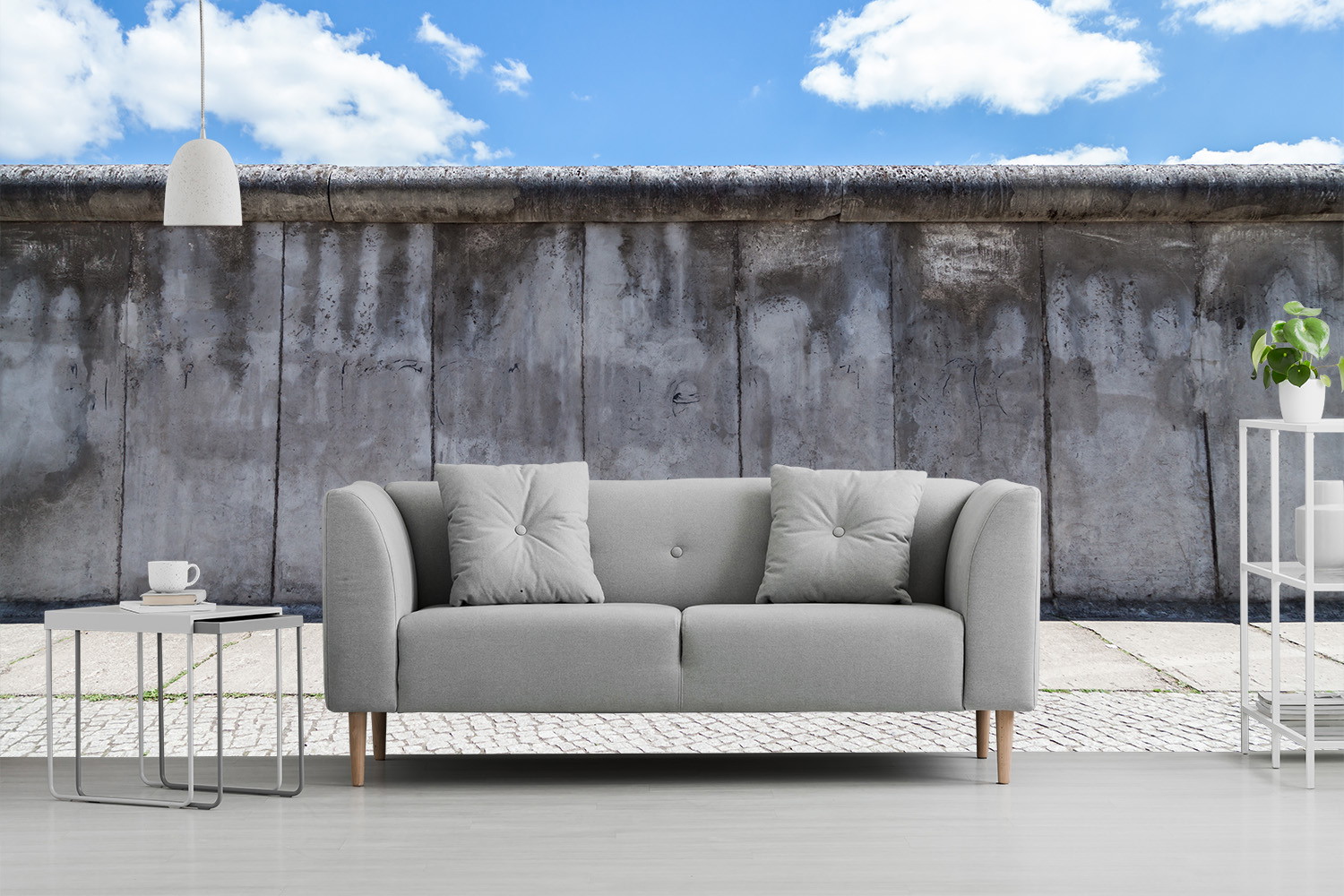 Fototapete - Graues Sofa und Couchtisch vor einer urbanen Mauer mit blauem Himmel im Hintergrund