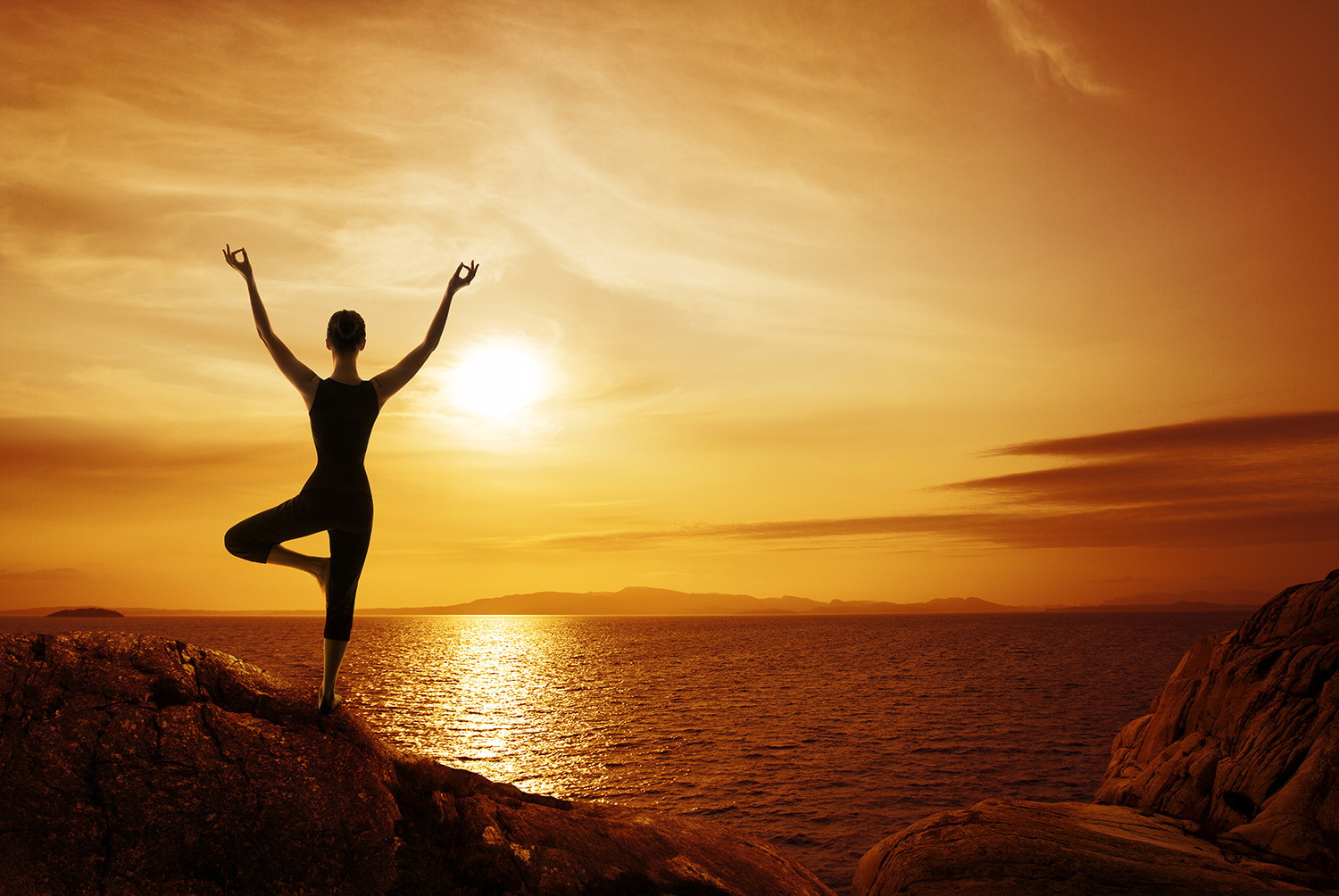 Fototapete - Frau meditiert in Yoga-Pose vor einem goldenen Sonnenuntergang über dem Meer