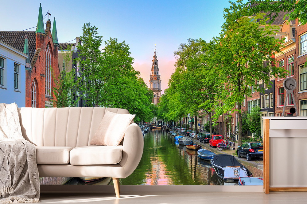 Papier peint photo - salon avec canapé devant une image d'un canal idyllique d'Amsterdam avec de vieux bâtiments et beaucoup de verdure