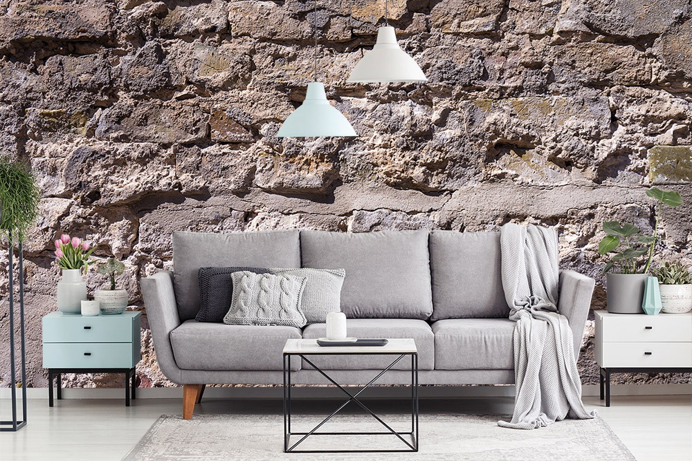 Fototapete - Stilvolles Wohnzimmer mit grauem Sofa, Dekorationen und Tapete in Steinmauer-Optik