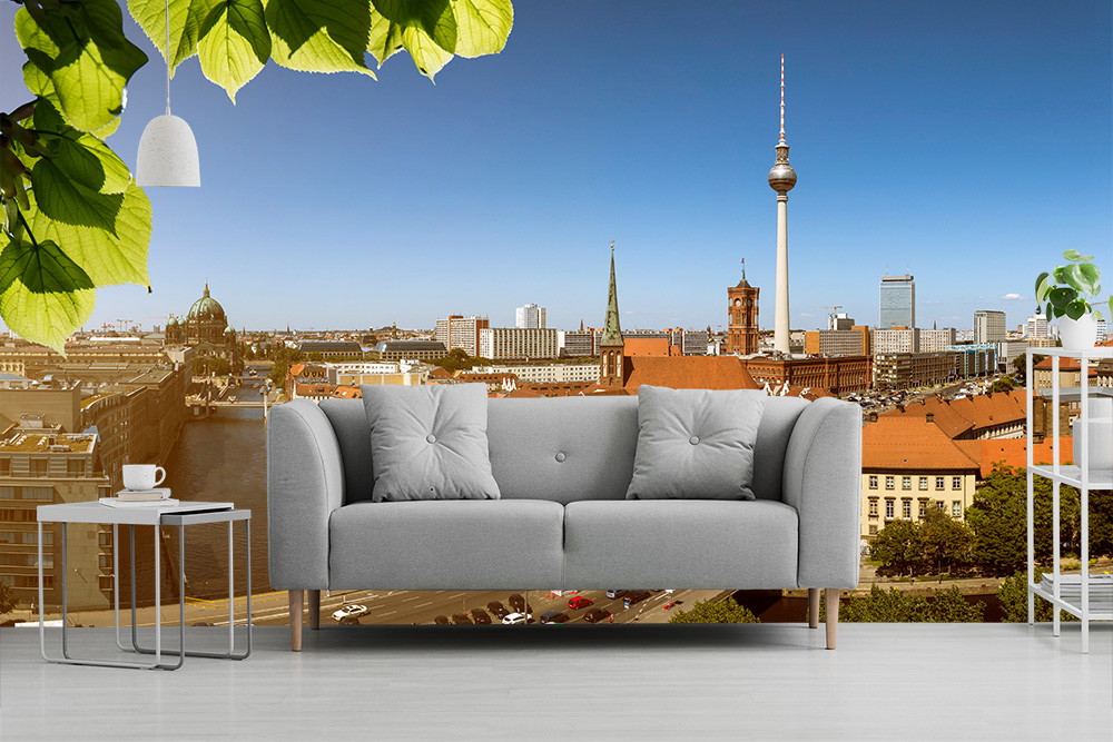 Fototapeta - Panorama Berlina z szarą sofą i nowoczesnymi meblami na pierwszym planie