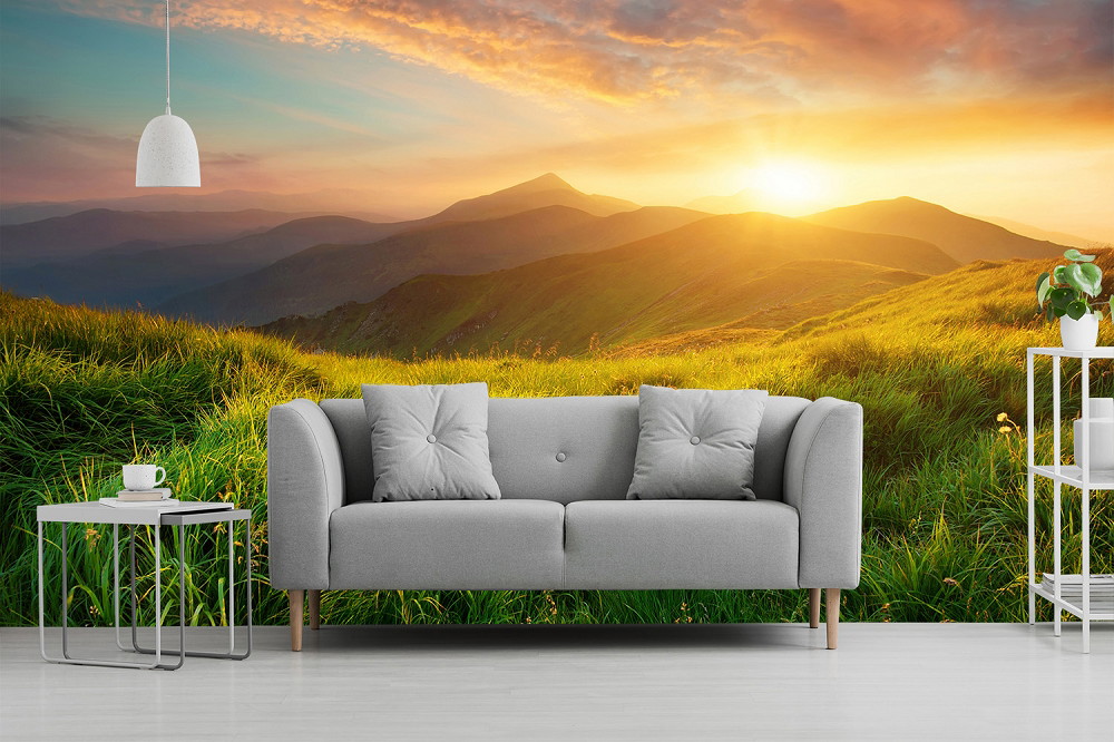 Fototapete - Wohnzimmer mit grauem Sofa und Fototapete eines strahlenden Sonnenuntergangs über grünen Hügeln