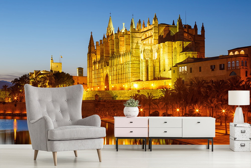 Fotobehang - Woonkamer met fauteuil en dressoir met op de achtergrond de kathedraal van Palma de Mallorca bij zonsondergang