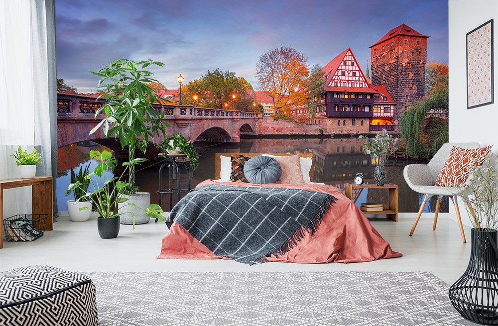 Fototapete - Elegantes Schlafzimmer mit Dekoration und großformatigem Wandbild eines Flusses und Fachwerkhauses im Sonnenuntergang