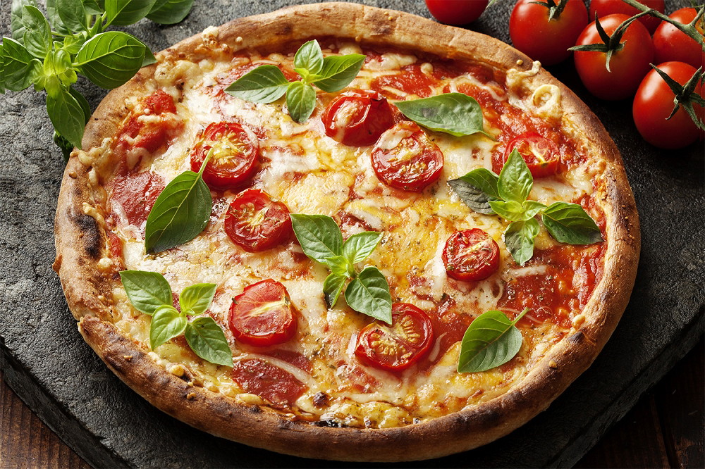 Muurschildering - Vers gebakken pizza Margherita met basilicumblaadjes en kerstomaatjes op een rustieke achtergrond