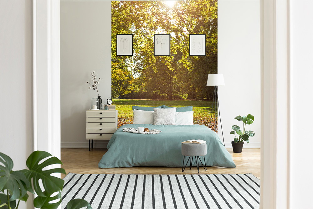 Fototapete - Schlafzimmer mit Bett in Grün- und Grautönen, umgeben von Naturmotiv-Wand, Pflanzen und heller Dekoration