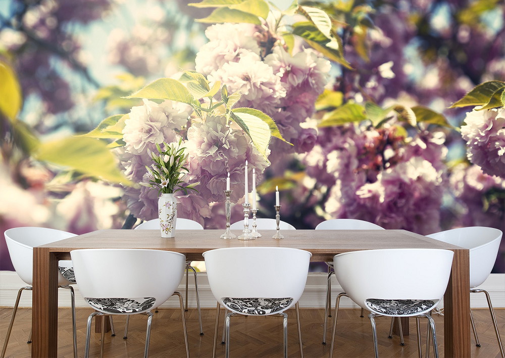 Wall mural - Dining area with wooden table, modern white chairs and wallpaper of blooming cherry blossoms in the background