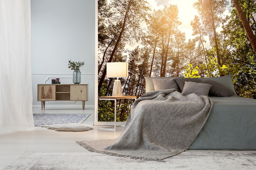 Fototapeta - sypialnia z tapetą przedstawiającą las z promieniami słońca, elegancki nowoczesny design z szarą narzutą i drewnianym dekorem