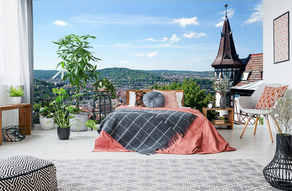 Wall mural - Bedroom with plants, modern furnishings and a view of an idyllic town with a historic building
