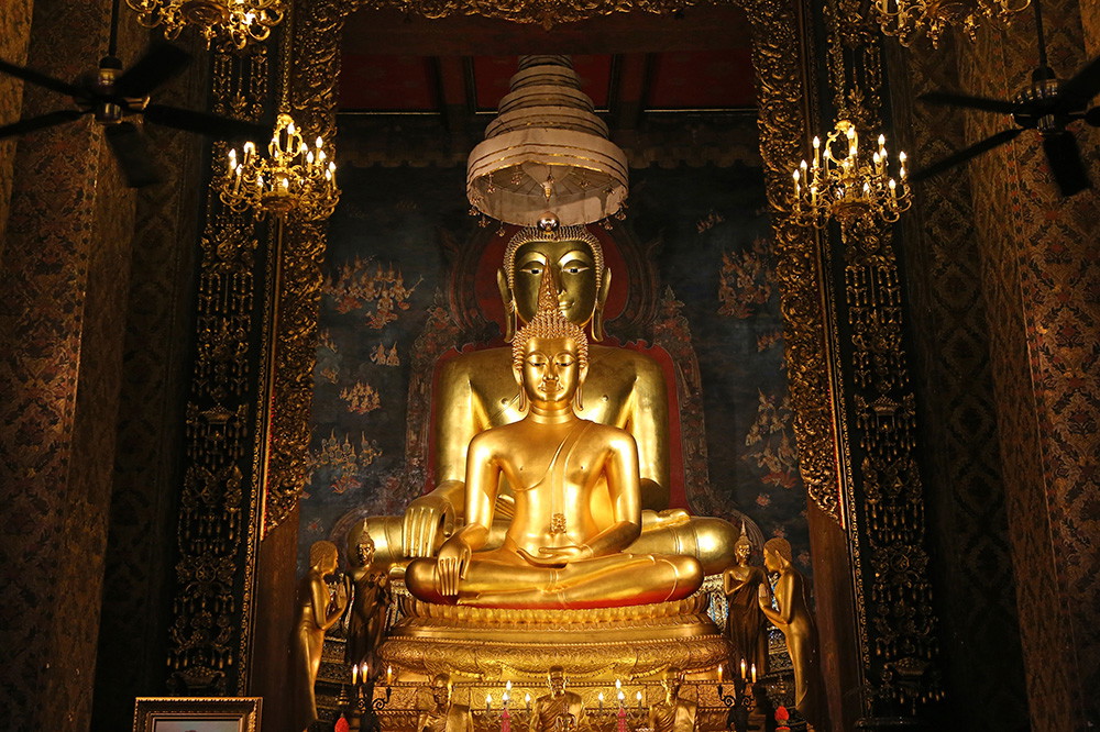 Fototapete - Goldene Buddha-Statue im Tempel, umgeben von aufwendigen Ornamenten und Kerzenlicht