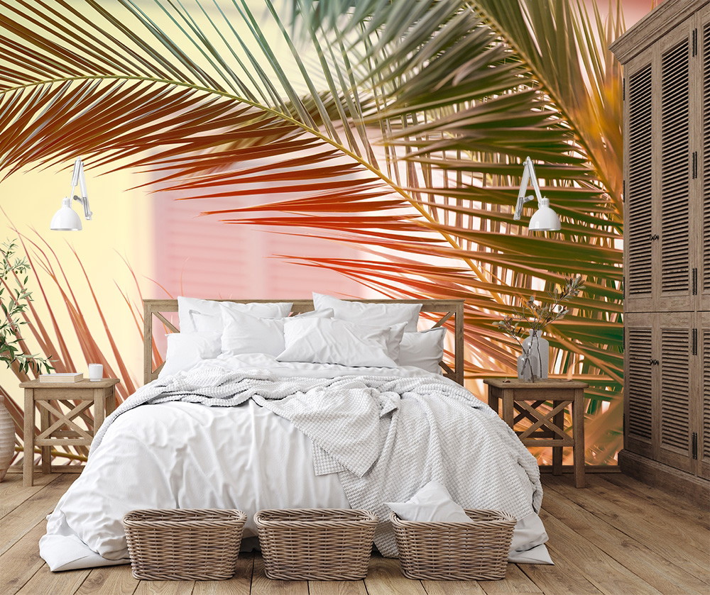 Fototapete - Schlafzimmer mit weißen Bettdecken, Holzmöbeln und Palmenblattmotiven an der Wand für tropisches Flair