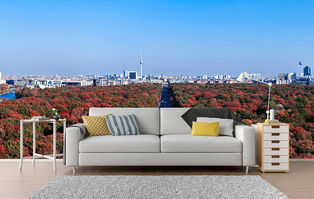 Fototapete - Wohnzimmer mit Sofa und Dekoration vor herbstlichem Stadtpanorama und Fernsehturm