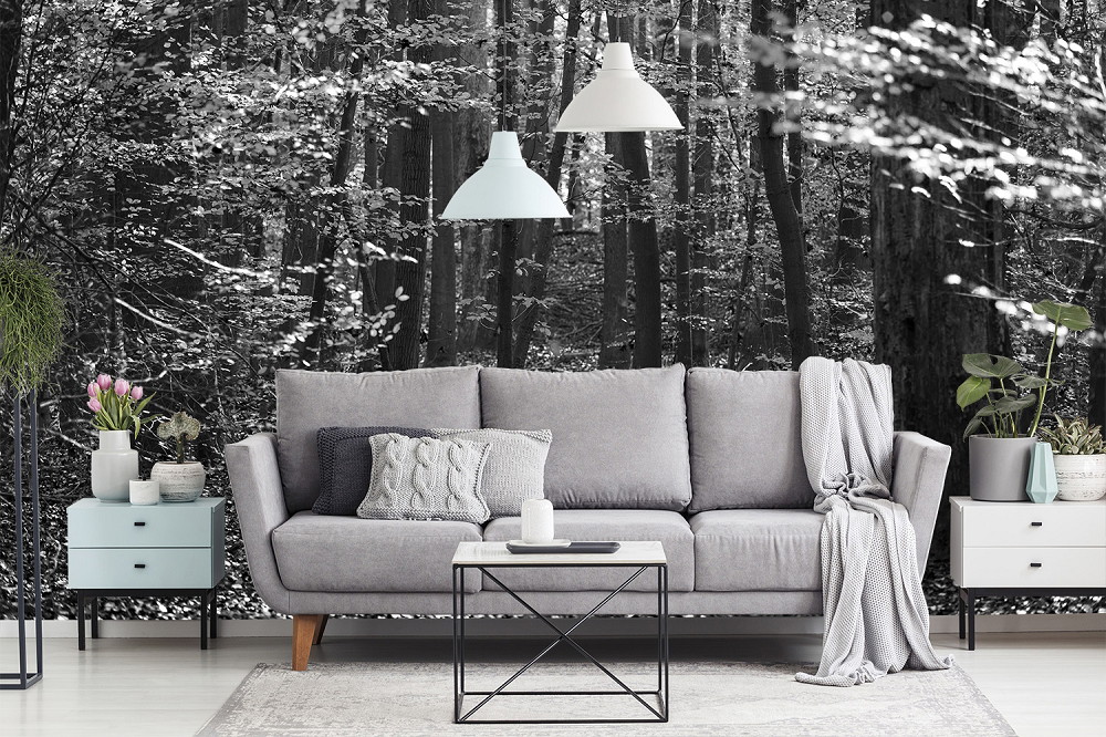 Fototapete - Gemütliches Wohnzimmer mit grauem Sofa, modernen Hängeleuchten und schwarz-weißer Waldtapete im Hintergrund