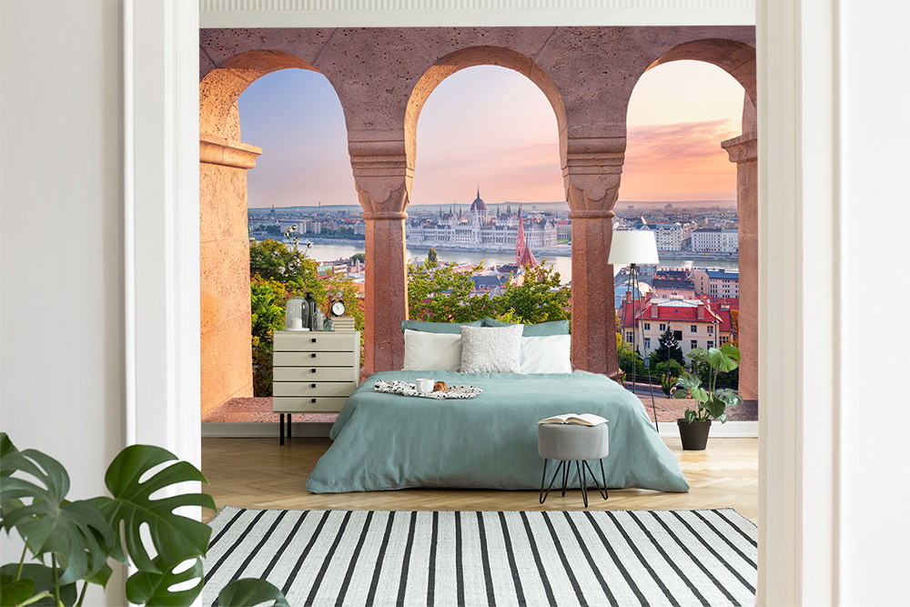 Fototapete - Modernes Schlafzimmer mit Blick auf eine Stadt durch dekorative Bögen, stilvoll eingerichtet mit Pflanzen und Teppich
