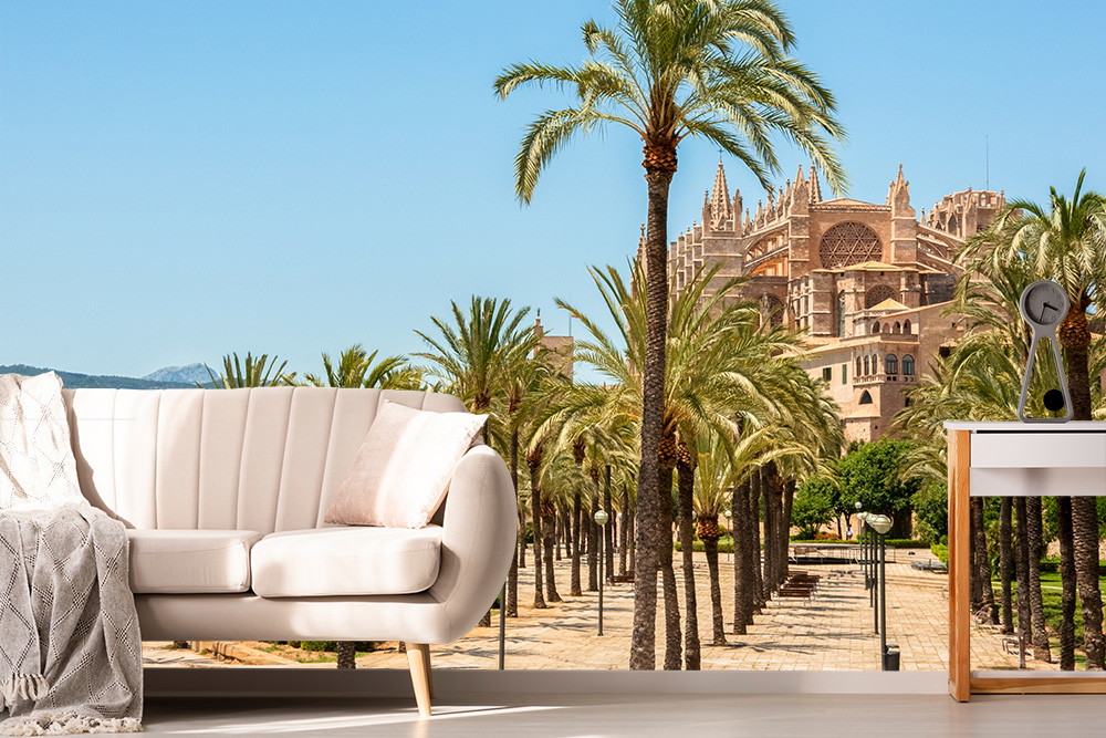 Wall mural - Bright living room with white sofa, palm avenue and historic cathedral in the background