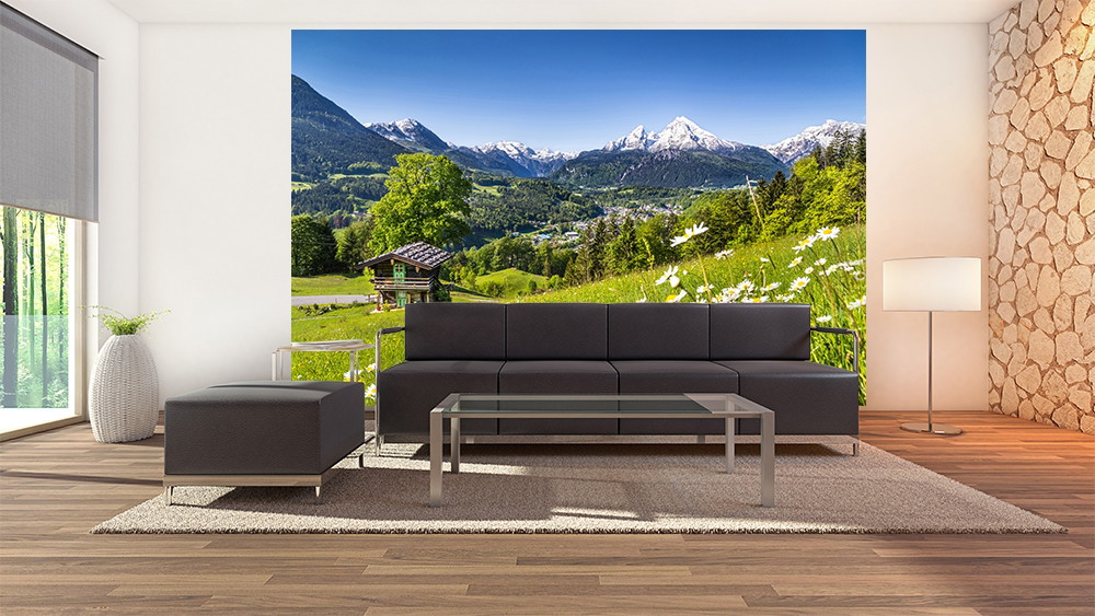 Fototapete - Moderne Wohnzimmereinrichtung mit Wandbild einer alpinen Landschaft, Berghütte, Wiese und schneebedeckten Bergen