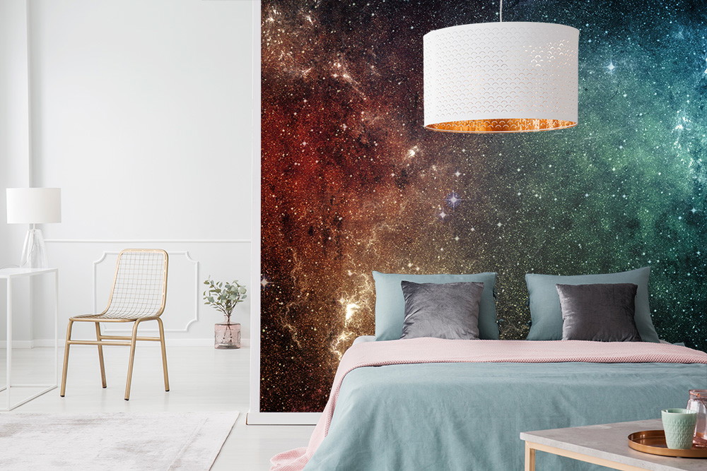 Fototapete - Buntes Galaxie-Motiv im Schlafzimmer hinter einem stilvoll eingerichteten Bett mit moderner Lampe