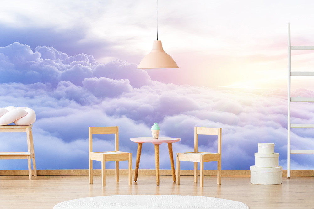 Fototapete - Ein Kinderzimmer mit Stühlen und einem Tisch vor einer Tapete, die eine Wolkenlandschaft mit Sonnenaufgang darstellt.