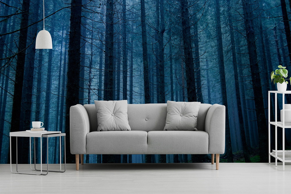 Papier peint photo - salon avec canapé gris, devant une image d'une forêt bleue et mystique