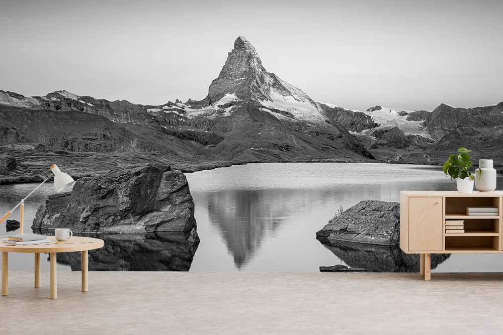 Papier peint photo - Photographie en noir et blanc d'une montagne avec un lac et des rochers au premier plan