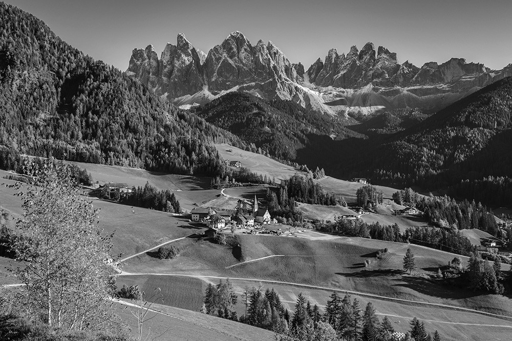 Fototapeta - Malowniczy górski krajobraz Dolomitów w czerni i bieli z idylliczną wioską na pierwszym planie