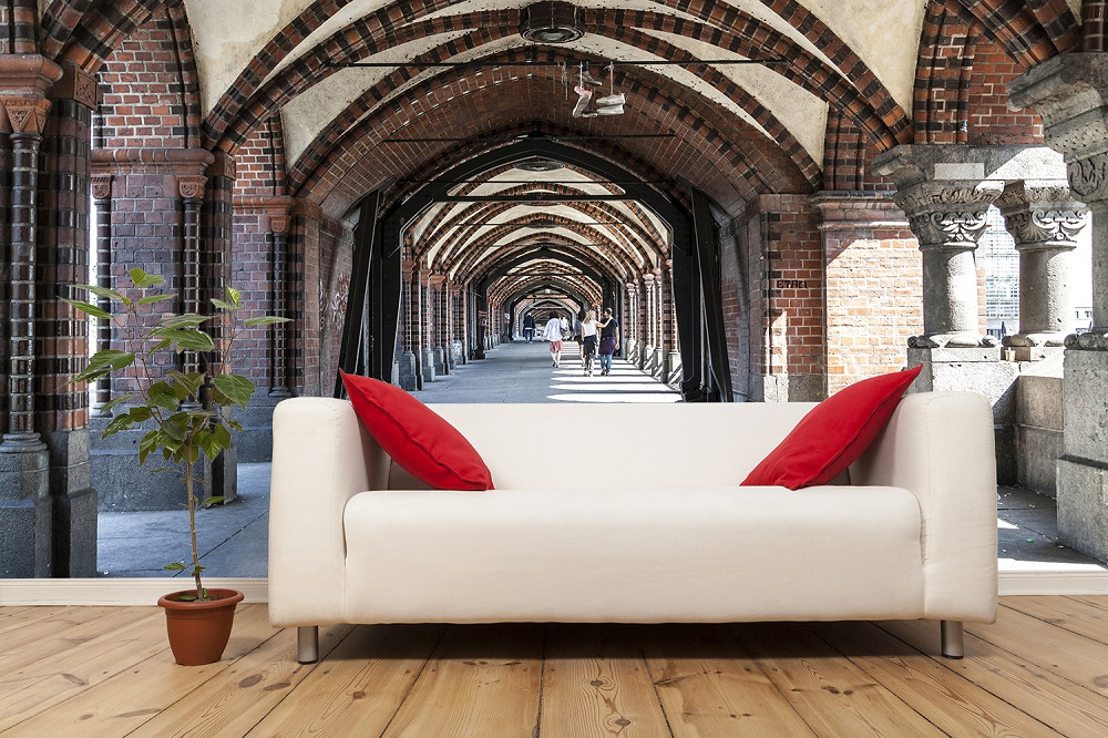 Fototapete - Historischer Gang mit Ziegelbögen hinter einem weißen Sofa mit roten Kissen