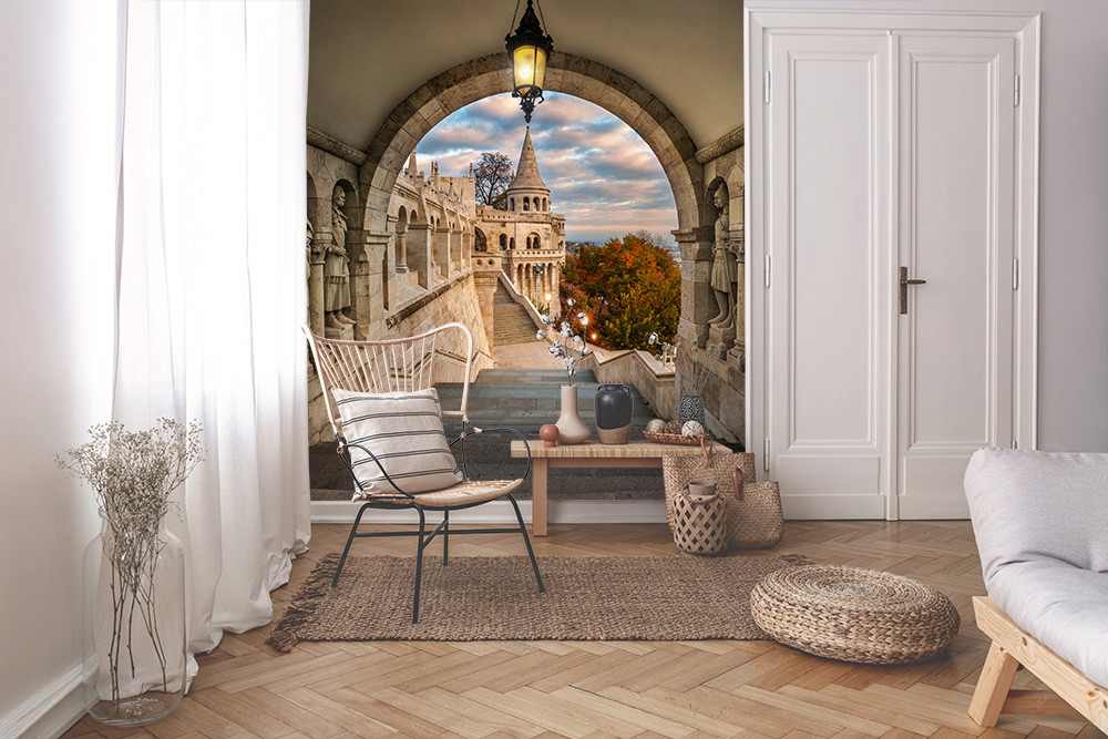 Papier peint photo - vue à travers une arche de pierre sur un vieux bâtiment et des arbres d'automne, sous un ciel nuageux